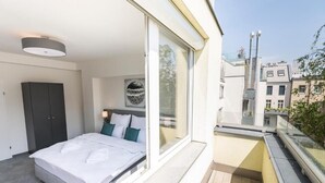 A bedroom with a bed, a wardrobe, and a large window. - Cube Apartments by Wiener Stadthalle (Vienna)