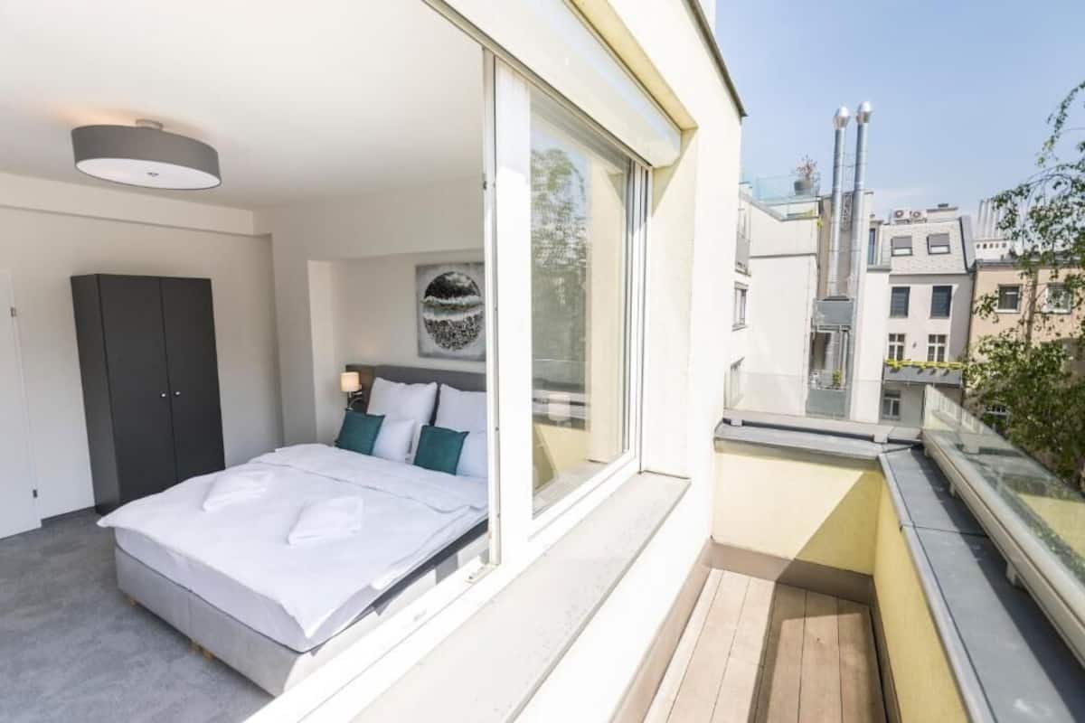 A bedroom with a bed, a wardrobe, and a large window.