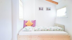 Un dormitorio con estructura de cama de madera, ropa de cama blanca y dos cuadros en la pared.
