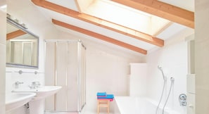 Een moderne badkamer met dakraam, douche, wastafel en toilet.