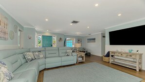 Ein Wohnzimmer mit Ecksofa, Fernseher, Couchtisch und Teppich.
