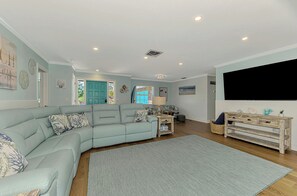 Ein Wohnzimmer mit Ecksofa, Fernseher, Couchtisch und Teppich.