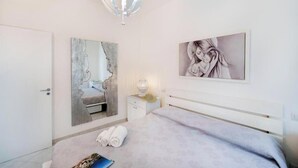 A bedroom with a bed, a bedside table, a lamp, a mirror, and artwork on the wall. - Belvedere Apartment - Breathtaking sea view with terrace in Nerano (Nerano)