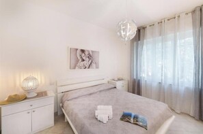 A bedroom with a bed, a bedside table, a lamp, a painting, and a window with curtains. - Belvedere Apartment - Breathtaking sea view with terrace in Nerano (Nerano)