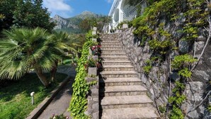 A stone staircase leading to a building with a white facade, surrounded by greenery and a mountainous backdrop. - Belvedere Apartment - Breathtaking sea view with terrace in Nerano (Nerano)