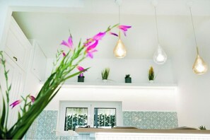 A modern kitchen with pendant lights, a window with a view, and a shelf with plants. - Incanto Apartment - Dream sea view with terrace and garden in Nerano (Nerano)