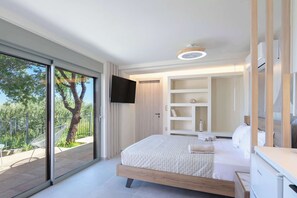 Une chambre moderne dotée d’un grand lit, d’étagères intégrées, d’un téléviseur et d’une porte-fenêtre coulissante donnant sur un espace extérieur.