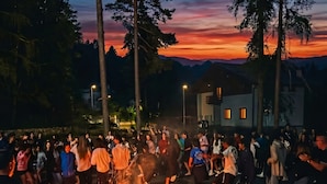 A stone-paved area with a fire, surrounded by people. - Garnì Pirata (Cavareno)