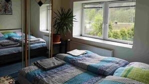 Ein Schlafzimmer mit zwei Betten, einem Fenster mit Blick, einem Spiegel und einer Zimmerpflanze.