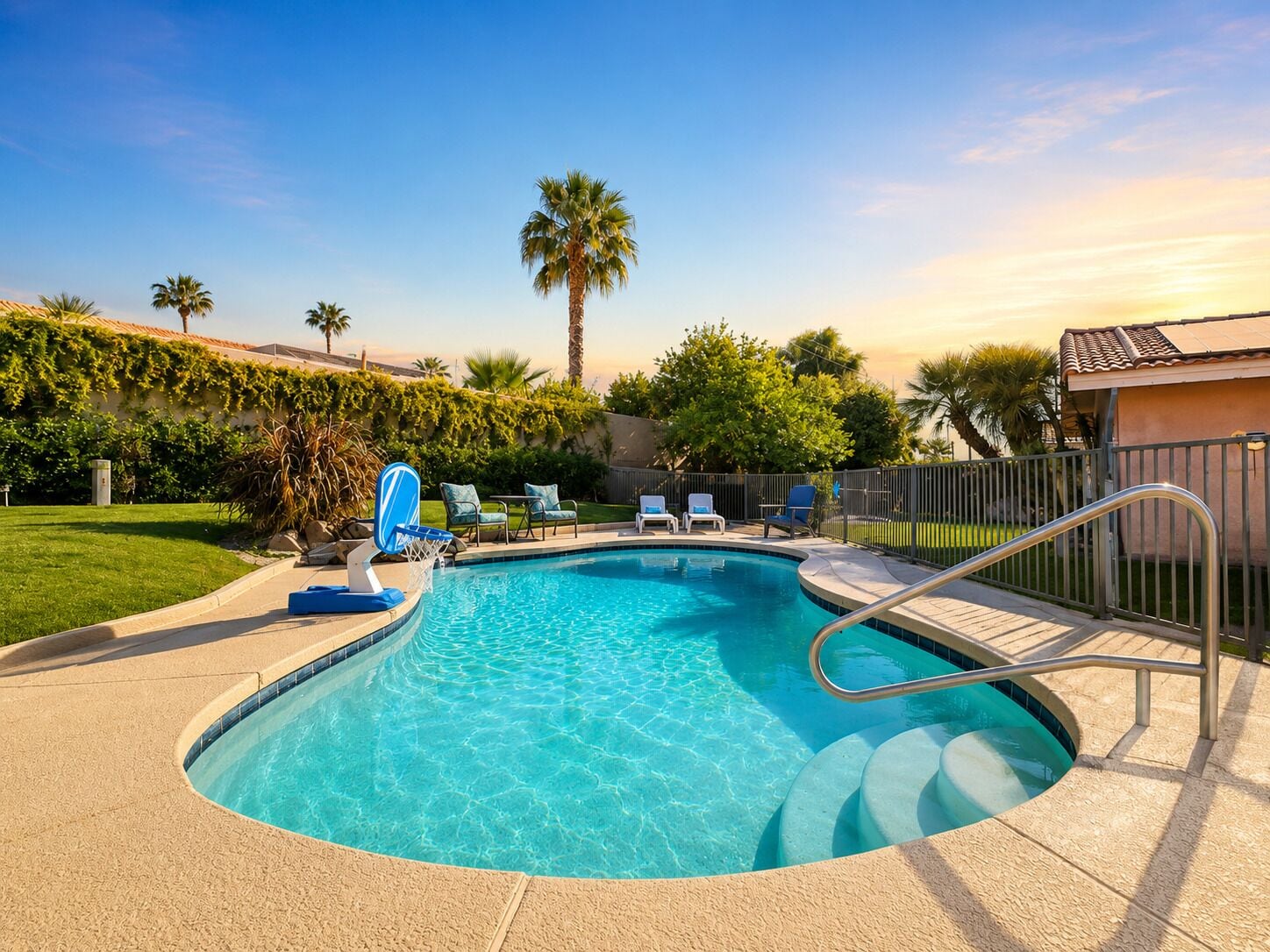 A swimming pool with a metal ladder, lounge chairs, and a palm tree in the background.
