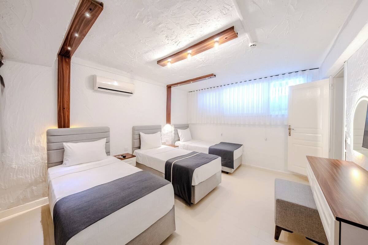 A hotel room with two beds, a desk, a chair, and a window with curtains.