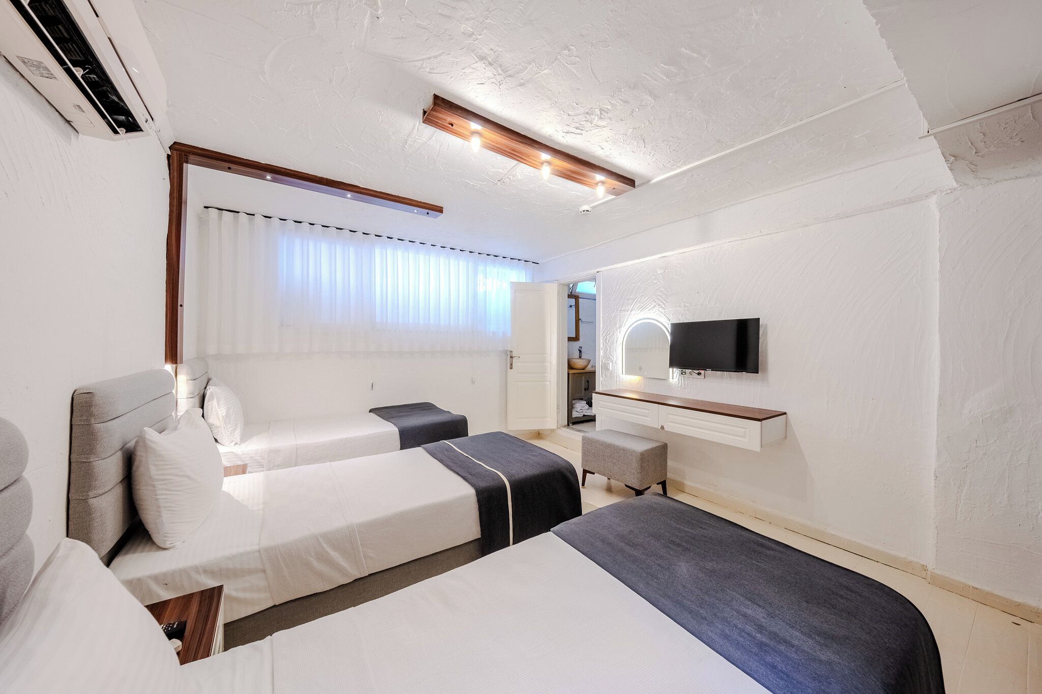 Habitación de hotel con dos camas, televisión, escritorio y ventana con cortinas.