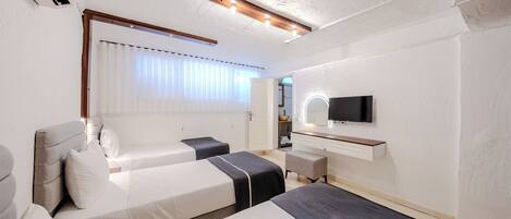 Habitación de hotel con dos camas, televisión, escritorio y ventana con cortinas.