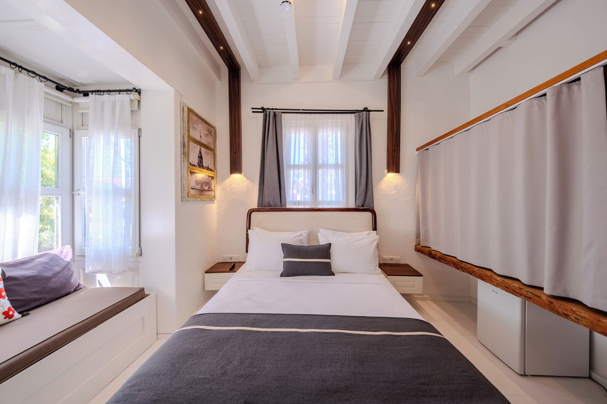 A bedroom with a bed, bedside tables, a window with curtains, and a painting on the wall.