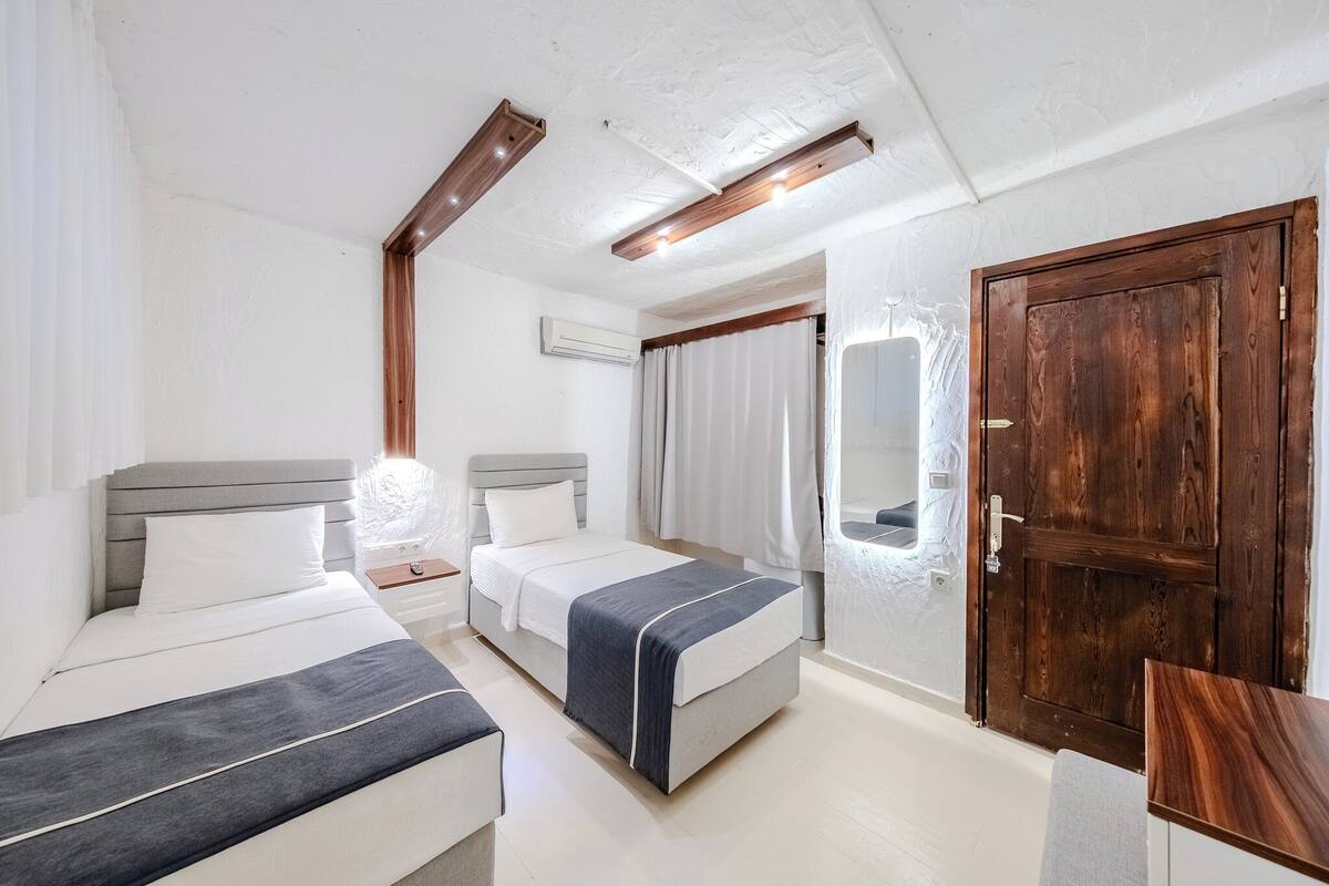 A hotel room with two beds, a wooden door, and a small table.