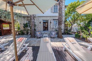 A stone building with a courtyard, outdoor seating, and lounge chairs. - B House Alaçatı (Cesme)