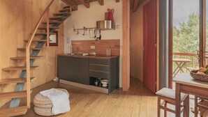 Een houten interieur met een keuken, een houten trap en uitzicht op het landschap.