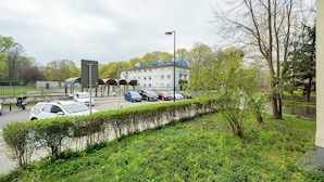 A building with a blue roof, a security car, and a row of parked cars. - RentPlanet - Studio Anielewicza (Warsaw)