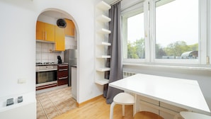 A modern kitchen with an archway leading to a dining area, a built-in shelf unit, and a window with a view. - RentPlanet - Studio Anielewicza (Warsaw)