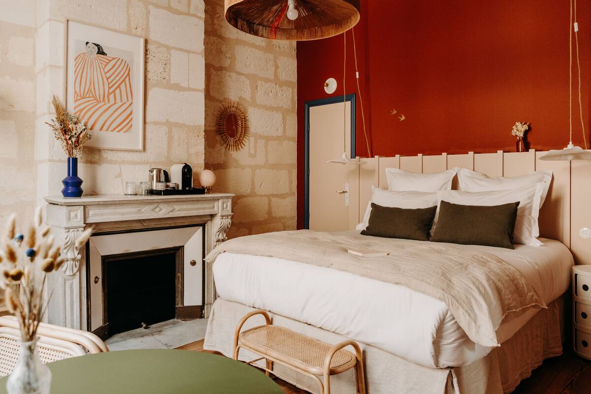 A bedroom with a bed, bedside table, and a fireplace.