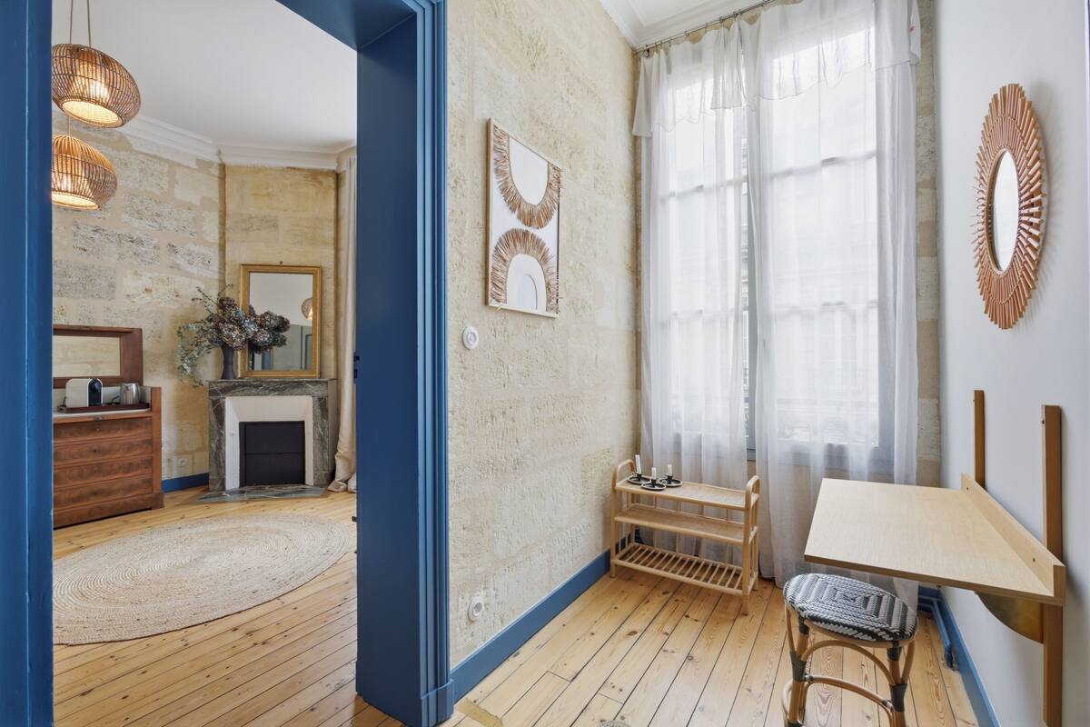 A room with a fireplace, a wooden table, a chair, and a mirror on the wall.