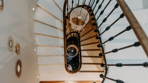 Una escalera de caracol con barandilla de madera y una pared blanca con apliques decorativos.