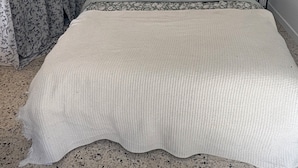 A bed with a woven headboard, two bedside tables with lamps, floral curtains, and a patterned bedspread. - Village house in a small hamlet in the heart of the Petite Camargue (Vauvert)