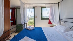 Quarto com cama, cortinas, vista para o exterior e janela.