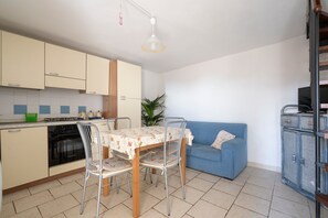Cocina compacta con mesa, sillas, sofá y televisor.