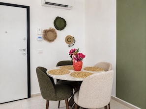 A dining area with a round table, four chairs, a vase with flowers, and wall decorations. - Bright, refined apartment in La Marsa (Marsa)