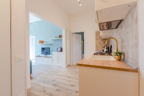 Eine moderne Küche mit Holzarbeitsplatte, Spüle aus Edelstahl und Armatur in Gold.