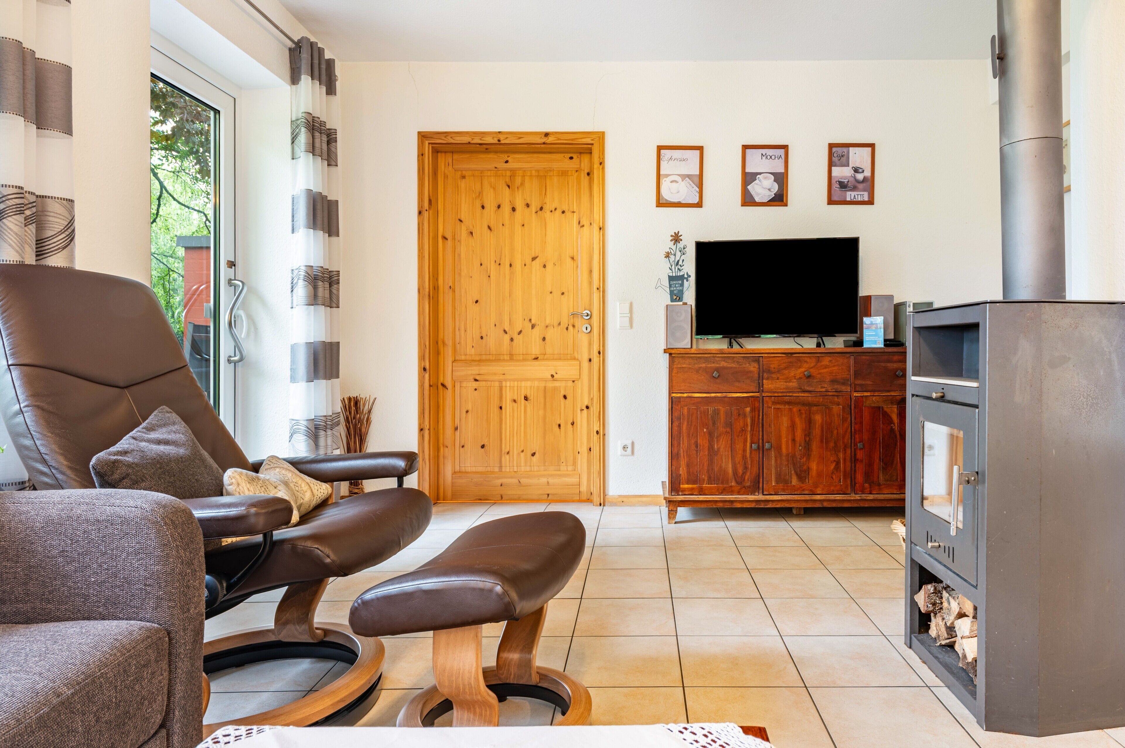 Una sala de estar con sofá, televisión, puerta de madera y chimenea.