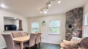 A dining area with a table and chairs, a stone accent wall, and a window with blinds. - Comfy 4BR Home on the Quietside [KelleyTown House] (Tremont)