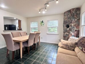 A dining area with a table and chairs, a stone accent wall, and a window with blinds. - Comfy 4BR Home on the Quietside [KelleyTown House] (Tremont)