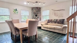 A living room with a dining table, chairs, a sofa, and a stone accent wall. - Comfy 4BR Home on the Quietside [KelleyTown House] (Tremont)