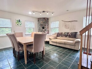 A living room with a dining table, chairs, a sofa, and a stone accent wall.
