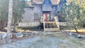 A wooden cabin with a red door, a wooden staircase, and a stone wall in front. - Comfy 4BR Home on the Quietside [KelleyTown House] (Tremont)