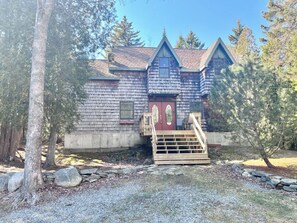 A wooden cabin with a red door, a wooden staircase, and a stone wall in front. - Comfy 4BR Home on the Quietside [KelleyTown House] (Tremont)