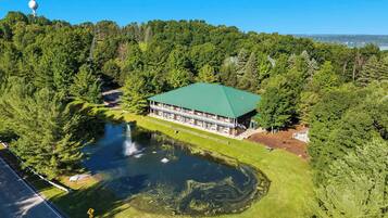 Eine Lodge mit Gründach, umgeben von dichtem Wald und einem Teich mit Wasserfall.