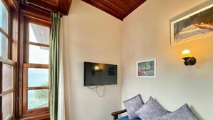 A room with a bed, a television mounted on the wall, a painting, and a window with curtains. - Ulivo Hotel (Antalya)