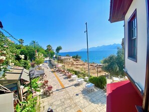 A terrace with outdoor seating, a view of the sea, and mountains in the background. - Ulivo Hotel (Antalya)