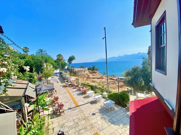 A terrace with outdoor seating, a view of the sea, and mountains in the background. - Ulivo Hotel (Antalya)