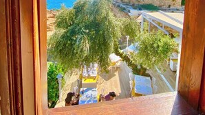 A view of a coastal area with a historic stone wall and a flag, through a window with wooden frames. - Ulivo Hotel (Antalya)
