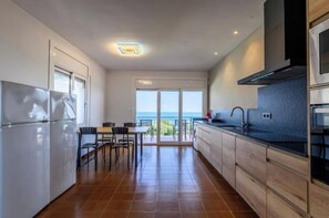 A modern kitchen with a view of the sea, a dining area, and a balcony. - Rooms Llançà - Serena Stays (Llançà)