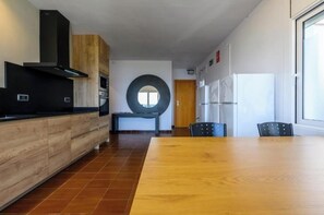 A modern kitchen with a wooden countertop, a black range hood, and a large circular window. - Rooms Llançà - Serena Stays (Llançà)