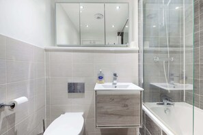 A modern bathroom with a toilet, sink, and shower area. - Stylish 2BDR House w Parking Near Heathrow (Berkshire)