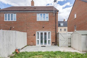 A brick house with a white door, a fenced backyard, and a satellite dish. - Stylish 2BDR House w Parking Near Heathrow (Berkshire)
