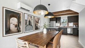 Un comedor con una mesa de madera, sillas y lámparas colgantes.