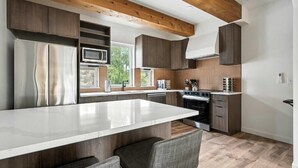 Una cocina moderna con una isla central, electrodomésticos integrados y techo de madera.