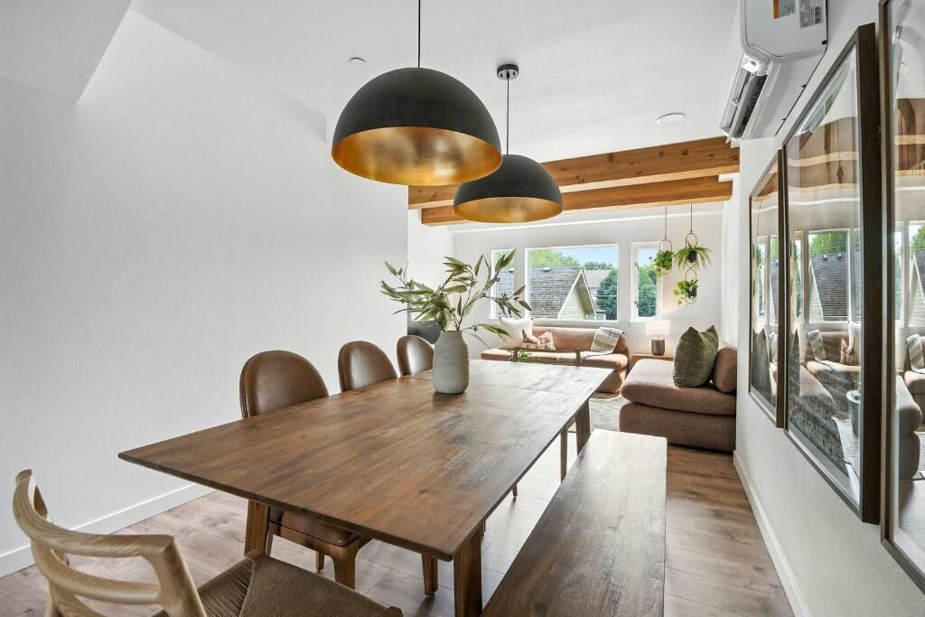 A modern dining area with a wooden table, chairs, and pendant lighting.
